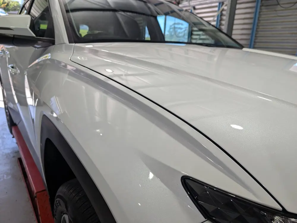 Close-up of a glossy white BMW bonnet and headlight