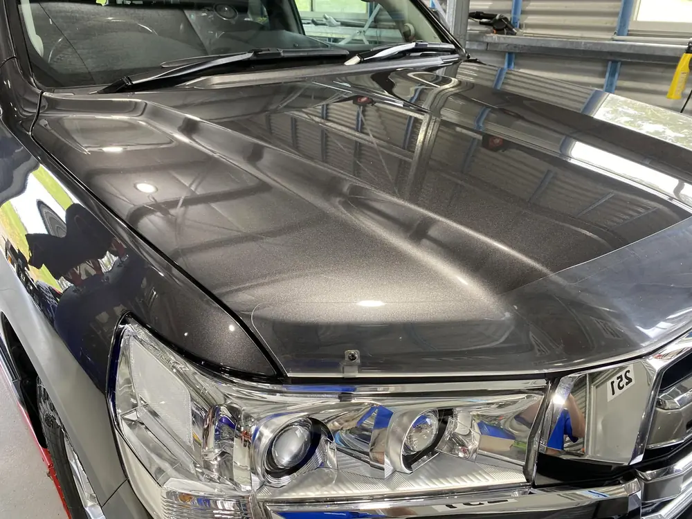 Close-up of a dark vehicle bonnet with a deep glossy reflection